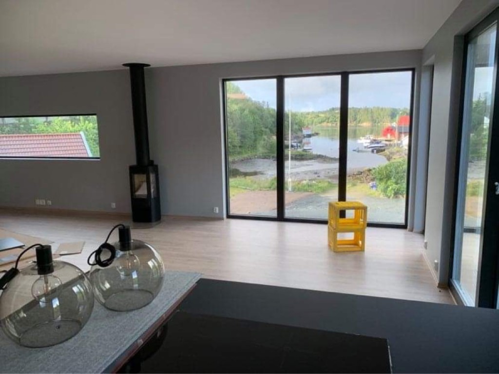 Åpen stue med store vinduer mot vannet i Villa Hellesund