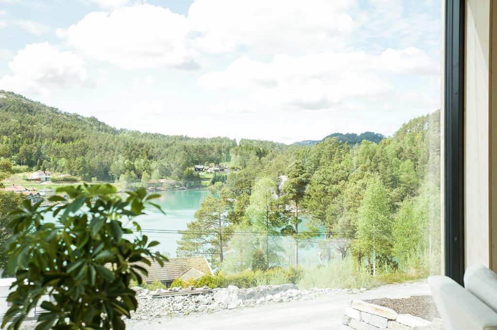 Utsikt mot vann og skog gjennom hyttevinduet