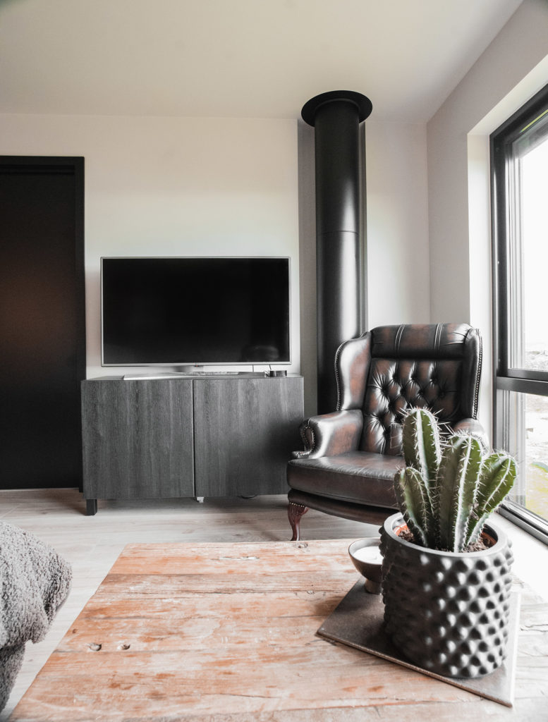 Stuekrok med skinnstol, TV og svart vedovn