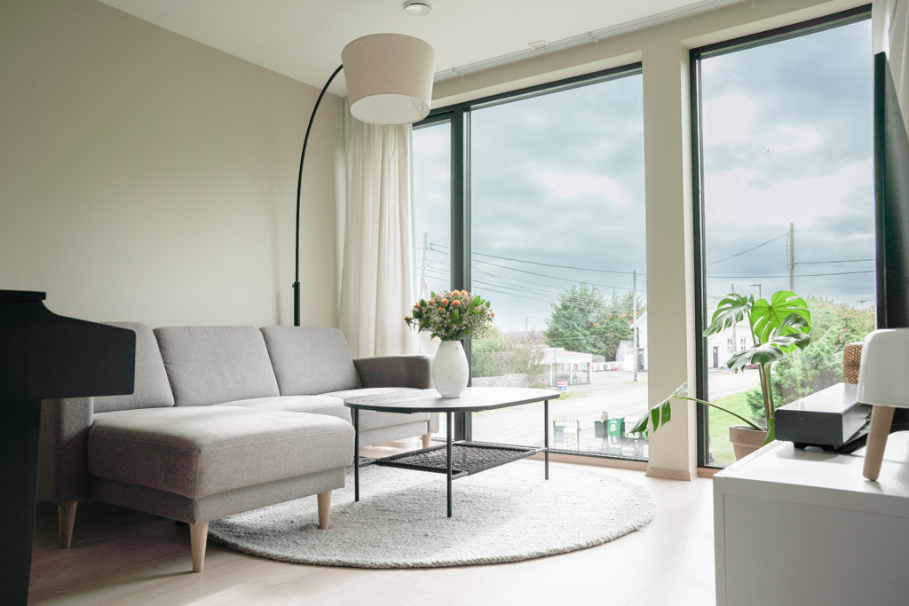 Sofa og salongbord foran vinduer fra gulv til tak