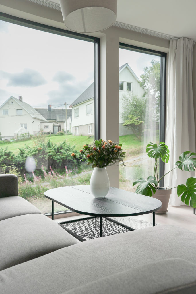 Blomstervase på bord foran store vinduer